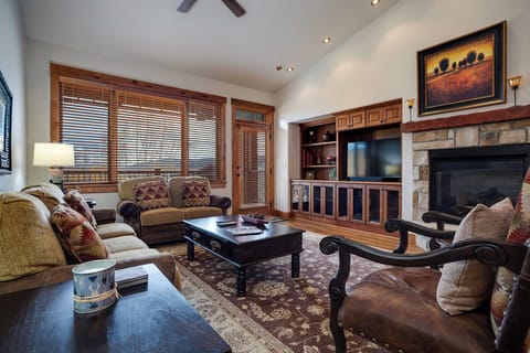Unwind in your elegant living room featuring warm wood details, stone fireplace, and premium furnishings for cozy mountain evenings.