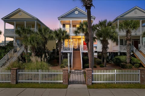 Charming beach house with classic coastal architecture, elevated design, and tropical palm landscaping in a peaceful residential setting.