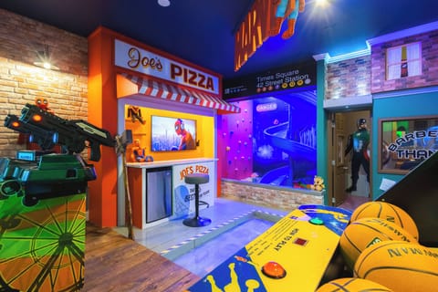 Experience fun in our vibrant game room featuring a playful pizza shop backdrop, colorful decor, and arcade-style games. The inviting lighting creates a lively atmosphere, ideal for memorable family entertainment.