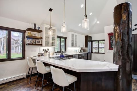 The modern kitchen boasts sleek cabinetry and a spacious island, perfect for preparing meals while enjoying picturesque views of the outdoors.