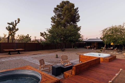 Backyard patio brings together the hot tub, cowboy pool and fire pit while enjoying the spacious backyard with beautiful desert trees and landscaping.