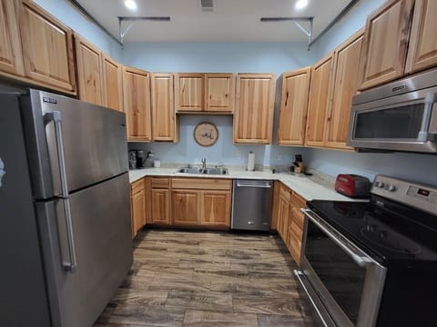 Fully equipped kitchen with stainless appliances, wood cabinets, and essentials.