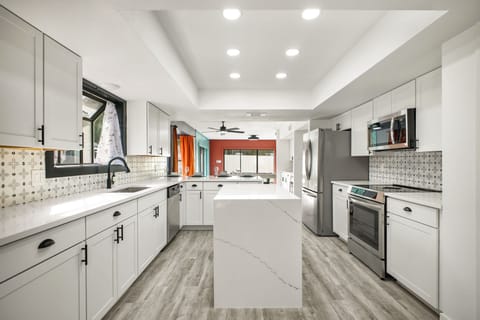 Full Kitchen: Bright open-concept kitchen with white cabinetry and quartz countertops. Southwest-inspired backsplash adds a stylish pop of design.