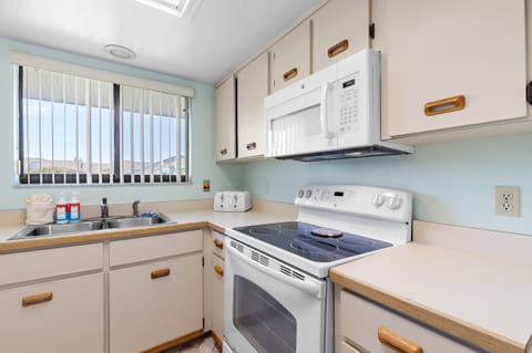 Whip up seaside meals in this bright, fully equipped kitchen featuring modern appliances, plenty of counter space, and natural light — perfect for your relaxing beach stay.