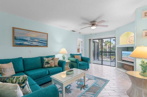 Relax in this bright, beach-themed living room featuring plush seating, coastal décor, and sliding doors to a private balcony — the perfect spot to unwind after a day of sun and surf at your seaside getaway.