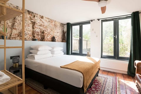 Spacious and full of character with a double bed under rustic brick walls and large windows.