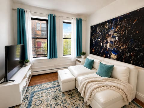 Sunny, city-chic lounge with comfy chaise, smart TV, and leafy views