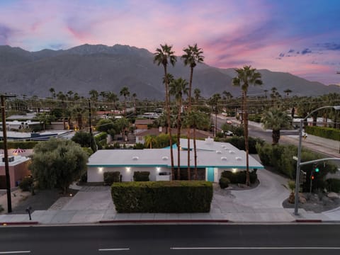 Sunset front view of the home with palm trees and a mountain backdrop.