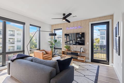 Bright living room with TV and large sunlit windows