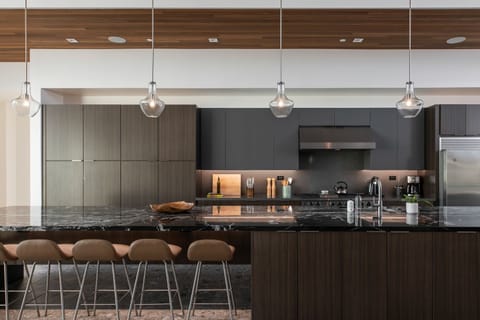 The gourmet kitchen island, featuring striking black marble, comfortable bar seating, and stylish pendant lighting.