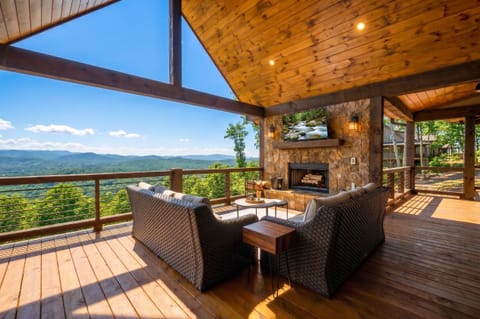 A stunning covered deck wraps around this mountain retreat, where a cozy stone fireplace and woven seating invite you to unwind while soaking in breathtaking, sweeping vistas of rolling ridges and endless blue sky.