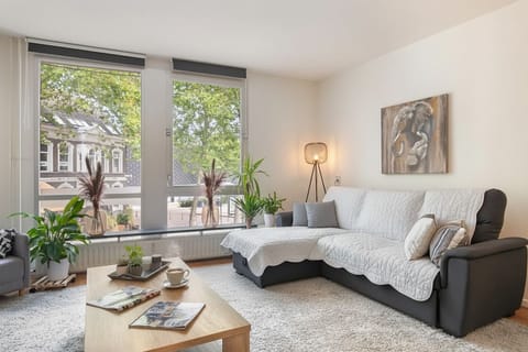 Bright living room with large windows, comfy sofa, and stylish decor – perfect for relaxing after exploring the city.