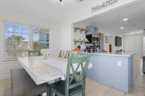 A bright and airy dining area with a rustic table and modern kitchen setup, perfect for shared meals and gatherings.