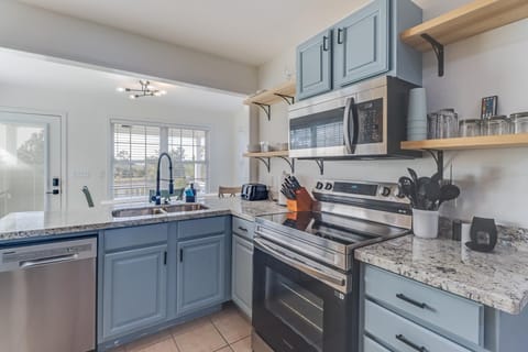 Designed for functionality, this cozy kitchen features sleek stainless appliances, ample counter space, and charming blue cabinetry, making meal preparation as enjoyable as dining.