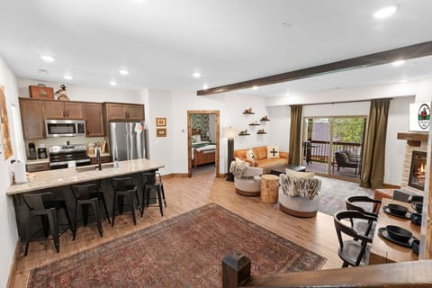 Spacious open-concept living area with a fully equipped kitchen, breakfast bar seating, cozy fireplace, and private balcony access—perfect for gathering, relaxing, and enjoying your Branson getaway.