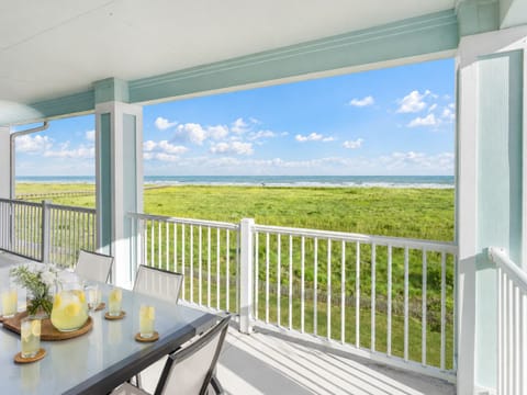 Private covered balcony with panoramic Gulf Coast views, outdoor seating, and peaceful marsh scenery. Perfect for morning coffee, sunset watching, and relaxing coastal escapes.