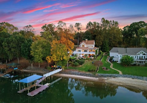 Aerial view of lakeside property with dock and boathouse.