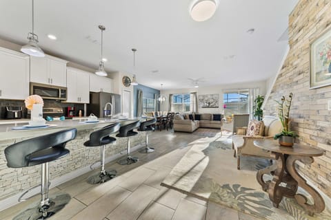 Sunlit open-plan living with a sleek kitchen, stone-accent breakfast bar, dining for the crew, and a comfy sectional for movie nights.