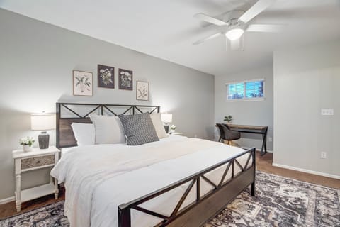 Spacious king master bedroom with clean white linens, a dedicated workspace, walk-in closet, and private en-suite bathroom.