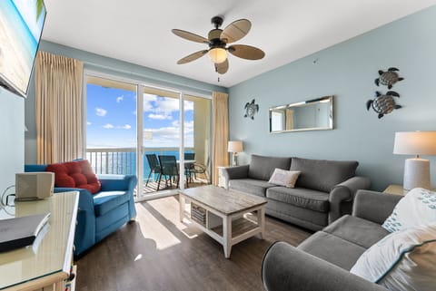 Bright living room w/ coastal blue walls, ocean views, & a ceiling fan to keep the breeze going.