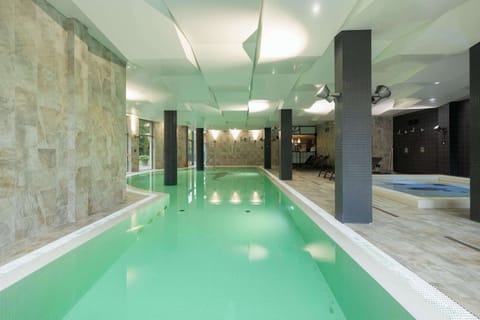 A serene indoor swimming pool area with wide windows offering natural light and a peaceful atmosphere for swimming and relaxation.