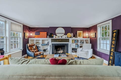 Cozy living room with stone fireplace, built-in bookshelves, and river views