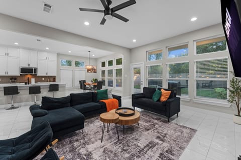 Bright space with big windows, navy sofas, cozy throws, and modern kitchen.