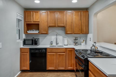 Fully equipped kitchen with warm wood cabinetry, tiled backsplash, and modern appliances for all your cooking needs