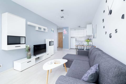 Cozy living room with a gray sofa, wall-mounted TV, and modern minimalist décor.