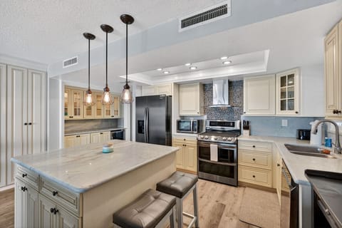 Open kitchen w/ spacious island seating, pendant lighting, & a bright layout made for gathering.