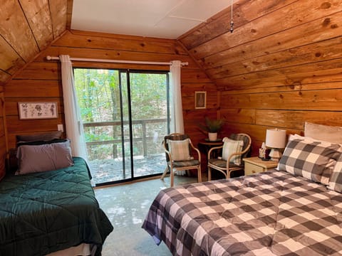 Wood-paneled bedroom with queen bed, twin bed, and forest views