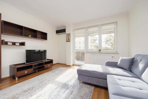 Bright living room with a large window and a soft corner sofa invites you to relax after a busy day, creating a space full of light and comfort.