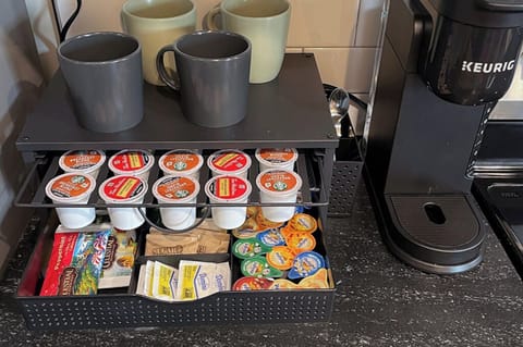 Keurig coffee station with pods, tea, sugar, and mugs ready anytime.