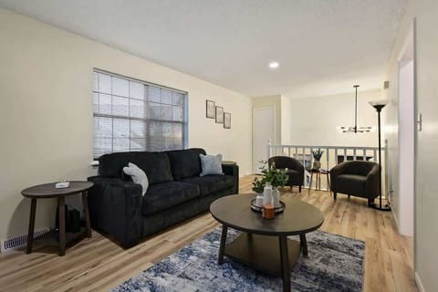 Bright and modern living room featuring a comfortable sofa, stylish seating area, and open-concept layout—ideal for families, business travelers, and groups visiting Kansas City. This cozy gathering space includes a smart TV setup, natural light from