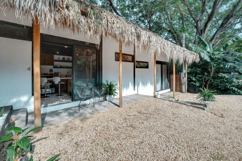 Unit 4 entrance — thatched roof, tropical greenery, sliding glass door 