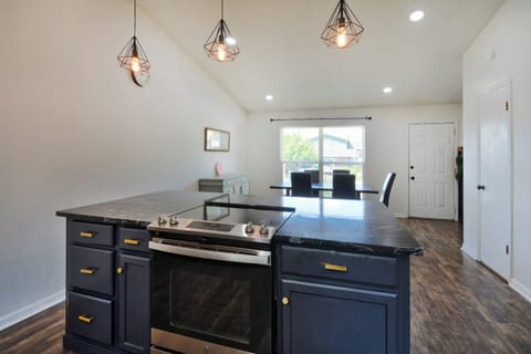 Your modern kitchen flows seamlessly into the dining area, where geometric pendant lights cast a warm glow over your meal prep and dining moments. The sleek island with built-in stove makes cooking a joy.