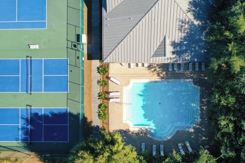 Aerial view of the property showing a sparkling swimming pool surrounded by mature trees and modern architecture.