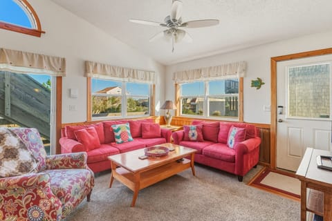The open-concept living room features cozy seating, coastal décor, and a flat-screen TV, creating a comfortable gathering space for the whole family.
