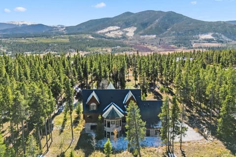Mountain lodge nestled among towering pines with dramatic peaks creating a stunning backdrop.