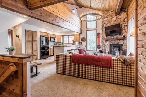 Cozy living room w/ vaulted ceilings, plush sectional, stone fireplace, & smart TV