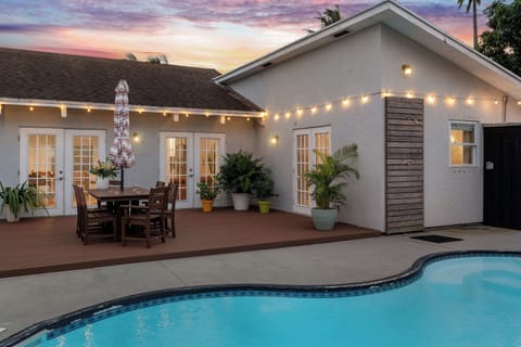 String lights and shade sails set the mood over the pool-deck dining table at dusk. - Pool Deck at Dusk - The Palm - West Palm Beach, FL