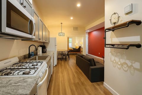 Galley kitchen with gas range, microwave, and double sink, opening to the living and dining area.
