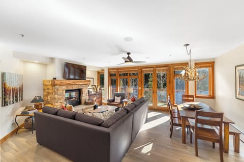 Unwind in your spacious living area with a cozy stone fireplace, plush seating, and elegant dining space bathed in natural light.