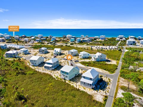 Aerial view of beachside vacation rental community with direct beach access and stunning coastal setting.