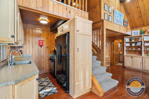 Open-concept comfort: A well-equipped kitchen flows seamlessly into the main living space, with stairs leading to the loft above. Designed for shared meals, easy mornings, and relaxed evenings under one roof.