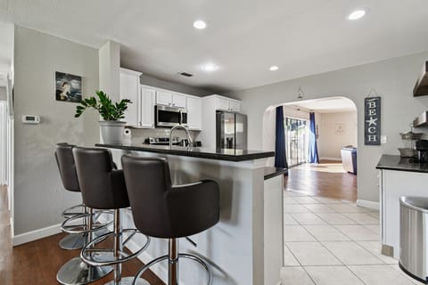 The kitchen features a sleek breakfast bar with four stools, perfect for casual meals or morning coffee.
