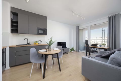 The bright living area combines a functional kitchenette with a cozy sitting space, creating the perfect setting for relaxation and shared moments.