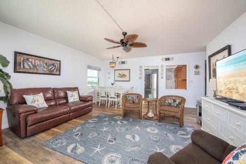 Relax in the coastal-themed living room with comfortable seating and a ceiling fan.