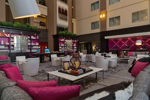 Cozy lobby with pink pillows, white chairs, and shelf decor