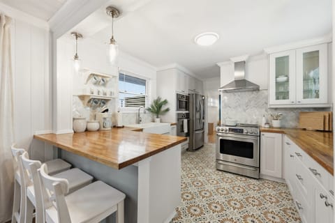 Fresh, bright kitchen with warm butcher block counters and stainless appliances — fully equipped for everything from quick beach breakfasts to family dinners at home.